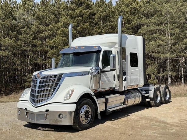 Semi truck with white cab and sleeper, International Lonestar model, front grille, exhaust stacks, chrome mirrors, and dual rear axles.