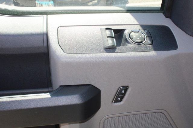 Vehicle interior door panel with mirror/adjustment control and window/lock buttons. Visible text includes small LED/knob labels but not clearly legible beyond basic control icons.