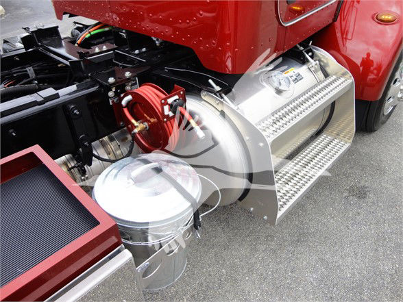Peterbilt truck side view showing stainless steel fuel tanks and stepped side steps with red cab, chrome wheels, and nearby hoses and piping.