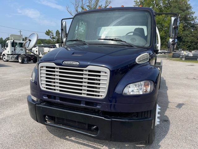 Front view of a dark blue 2013 Freightliner M2 truck with large chrome grille, rectangular headlights, and side mirrors. 