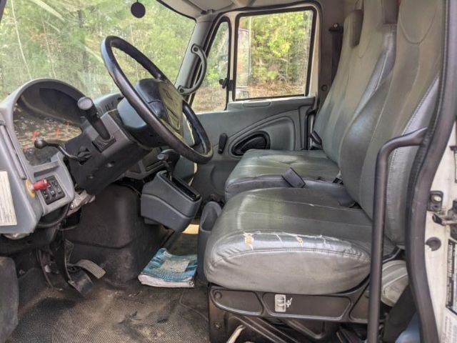 Interior cab of a 2005 International 4300 with driver and passenger seats, steering wheel, dashboard, and manual controls visible.