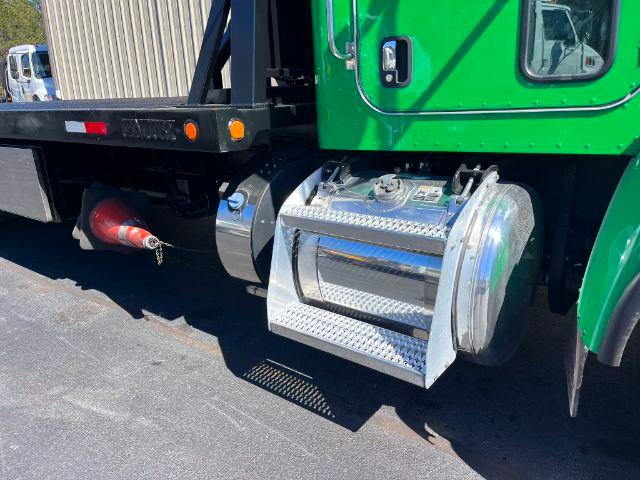 Peterbilt 348 truck side view with chrome fuel tank and diamond plate toolbox. Green cab, red jack/air hose, black frame, outdoor lot.
