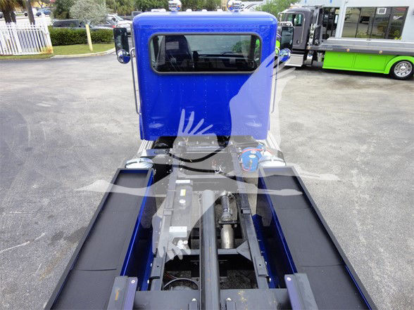 Peterbilt 337 cab and chassis view from rear showing blue cab, hitch area, and upraised hydraulic lines; truck bed rails visible.