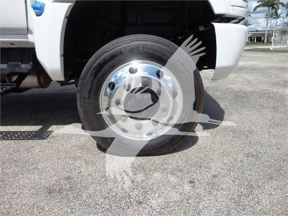 Truck wheel close-up showing aluminum rim with lug nuts and hub; part of white truck fender and front section visible.