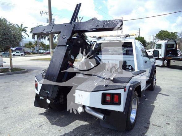 Utility tow truck rear view with large mechanical boom and hook, RAM logo watermarking on image, tail lights, exhaust pipe visible.