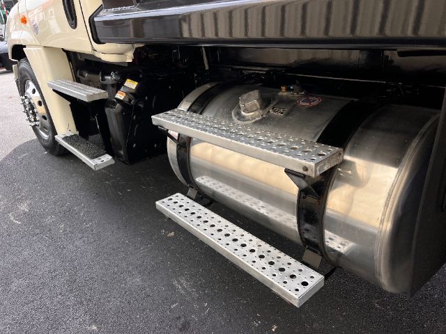 Freightliner Cascadia side view showing cylindrical fuel tank with metal step and platform, chrome fuel tank strap, on-road surface.