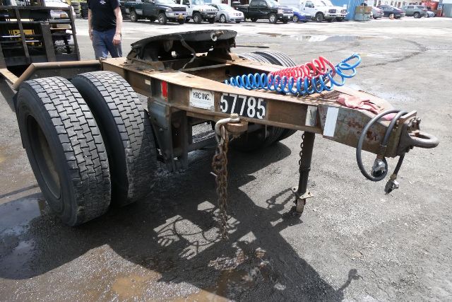 Trailer rear with dual wheels, tag numbers 57785 and YRC INC, coiled air hoses in red and blue on frame, hitch and chains visible.