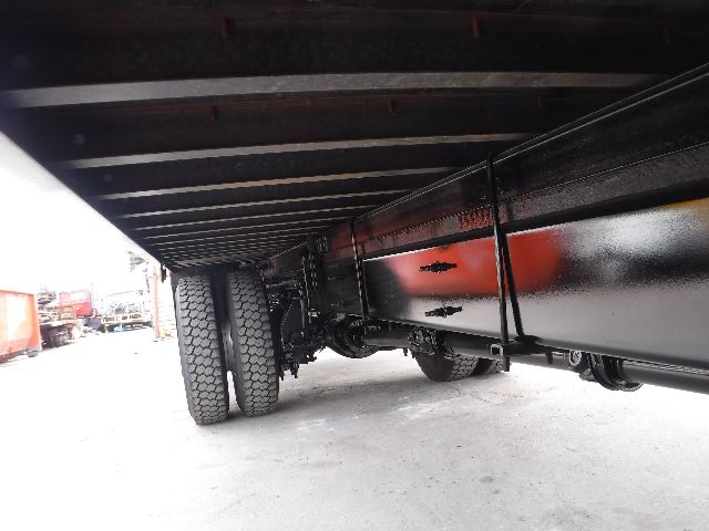 Underbody view of a flatbed truck showing twin rear wheels and undercarriage components.