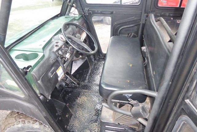 Cab interior of 2011 Kawasaki KAF950G utility vehicle showing steering wheel, dashboard, and black bench seat with footwell and door frame.