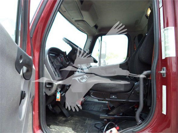 Truck cab interior showing driver's seat, steering wheel, pedals; partial view of door and floor; Freightliner branding not visible.