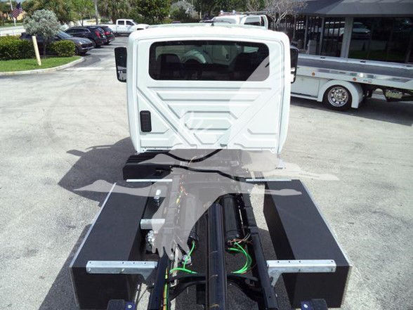 Truck cab rear view on a chassis with green wiring harnesses and black framework visible.