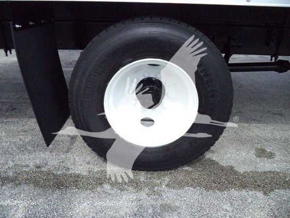 Truck wheel and tire under a box truck, white rim with black tire.