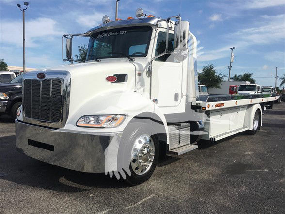 White 2022 Peterbilt 337 tow truck with flatbed, chrome grille, large side mirrors, and cab steps visible.