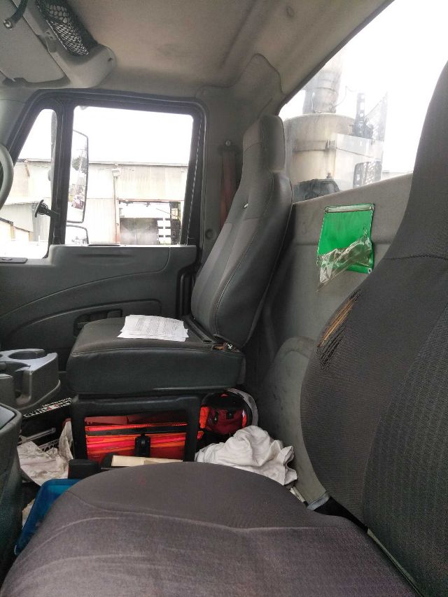 Inside of a 2006 International truck cab showing front seats, passenger seat, and scattered items on the floor.