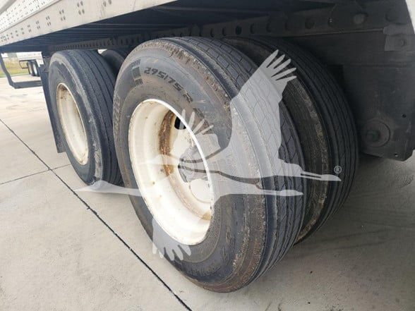 Wabash trailer axles and dual rear tires under trailer with white rims and tread detail visible.