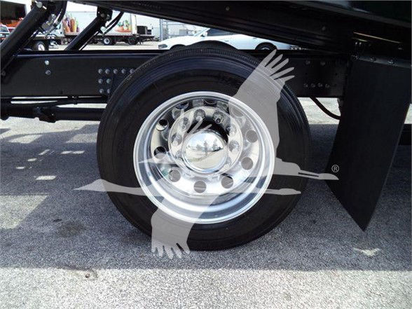 Wheel and chassis of a 2024 Mack MD6 truck showing an aluminum wheel and tire with fender and frame.