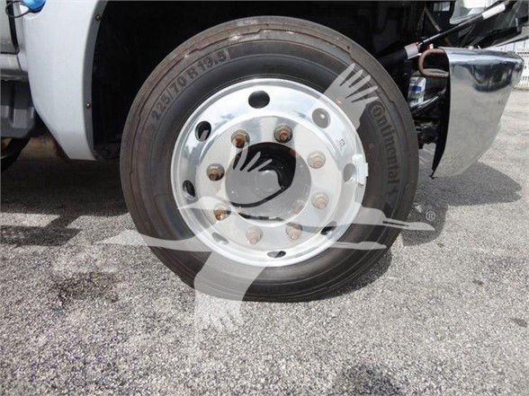 Front wheel and tire of a new 2023 Chevrolet Silverado 6500HD with chrome hub and lug nuts visible.