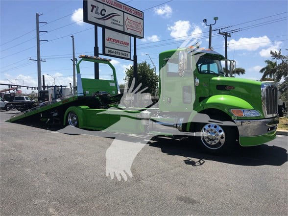 Green 2022 Peterbilt 337 tow truck with flatbed in a dealership lot.