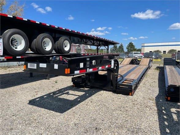 Fontaine 55 ton steel roller paver lowboy trailer with 24ft deck and black paint, showing flatbed outriggers and multiple axles in a yard.