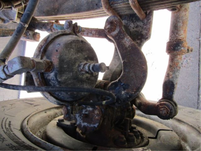 Mack CV513 truck undercarriage showing steering gearbox and suspension components with visible hoses and rust on metal surfaces.
