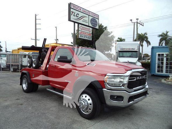Ram 4500 tow truck in red with dual rear wheels and flatbed, dealership lot in background.