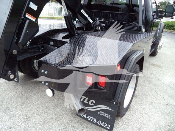 Ford F-450 tow truck bed and wheel area showing diamond plate metal steps and rear fender with TLC Truck Equipment decal.