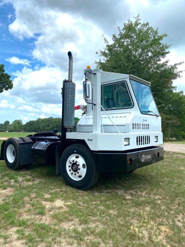 Truck cab of a 2003 Ottawa Commando 50 yard truck with slotted exhaust, white cab, and black chassis on grassy lot.
