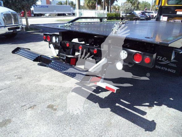 Truck bed with fold-down loading ramps and rear lights visible. Text on bumper area reads TCL and phone number digits partially visible. Diamond plate flatbed surface.
