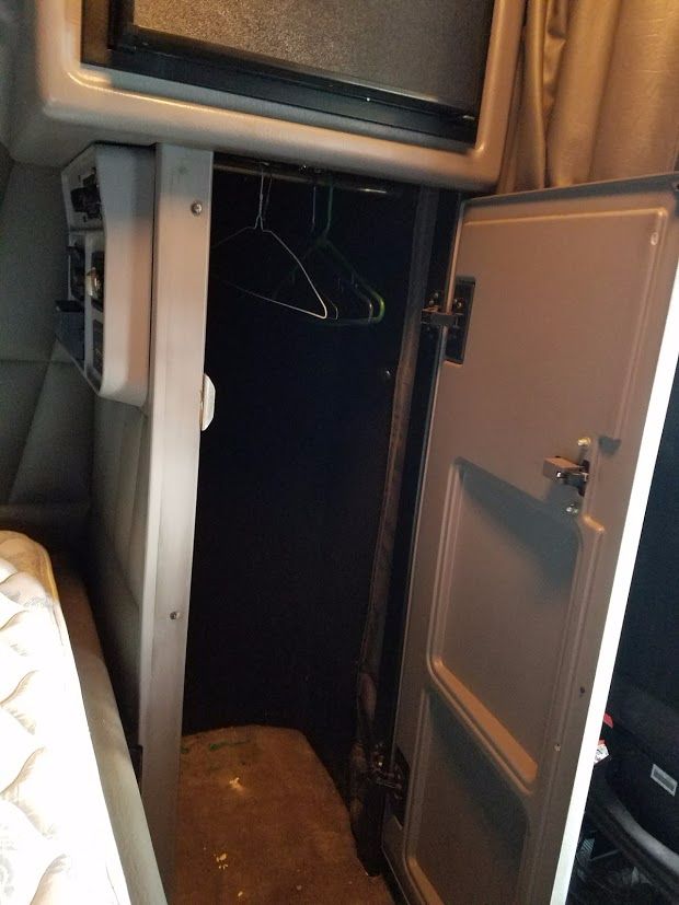Peterbilt 389 sleeper cab interior with open storage cabinet showing clothes hangers in a small hanging closet area.