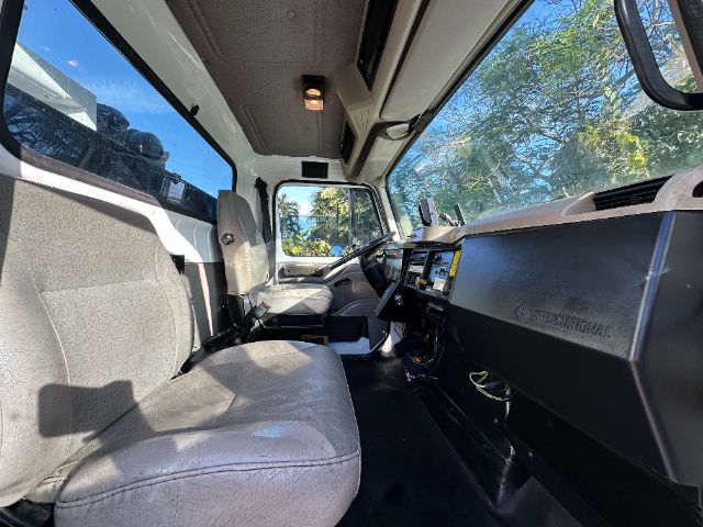 Interior of a 2001 International F-2554 vacuum/utility truck cab showing front bench seat, steering wheel, dashboard, and windshield.