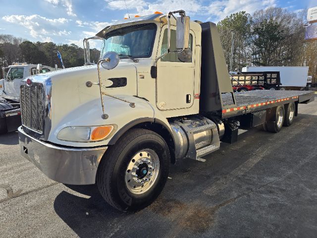 Peterbilt 348 rollback truck in beige with flatbed, front bumper chrome, large side mirrors, fuel tanks, and wheel wells. Cab features Peterbilt emblem; no visible text other than generic truck branding.
