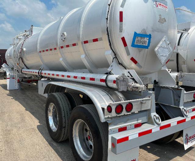 Crude oil tanker trailer with aluminum DOT-407 cylindrical tank, rear wheels, and safety markings. visible label stickers and reflective tape along the side.