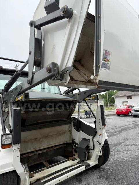 Truck-mounted Elgin Pelican NP sweeper component with raised hopper and cab area visible, showing hydraulic arms and open cargo bed.