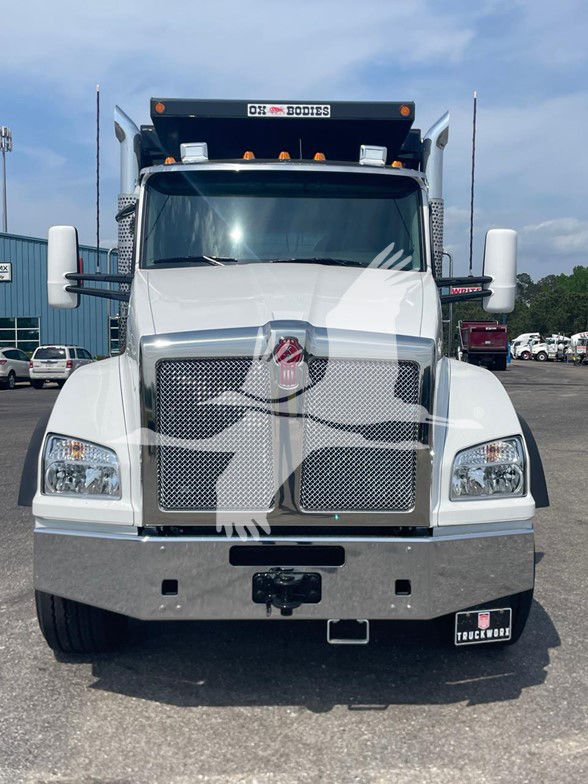 Kenworth T880 front view showing chrome grille, large bumper, and dual vertical exhausts; white cab with Kenworth emblem on grille.