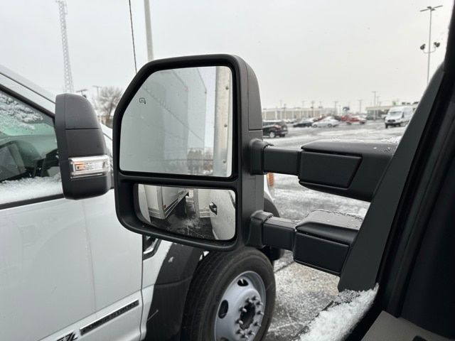 Side mirror view of a 2022 Ford F-550 truck showing exterior mirrors and part of the cab, with snow on ground.