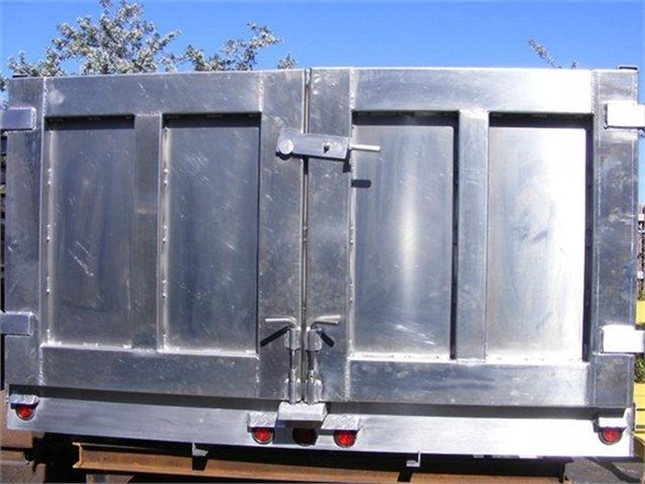 Dump body truck bed showing rear view with double doors and latch, metal panels, and safety lights along bottom edge.