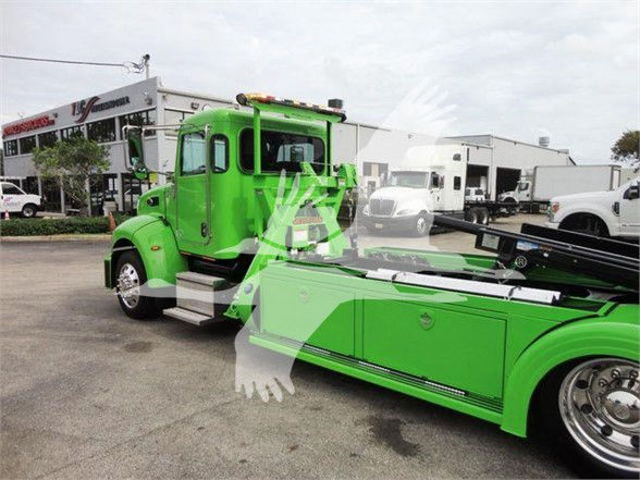 2022 Peterbilt 337 tow truck in bright green color with extended tow bed and toolbox compartments visible.