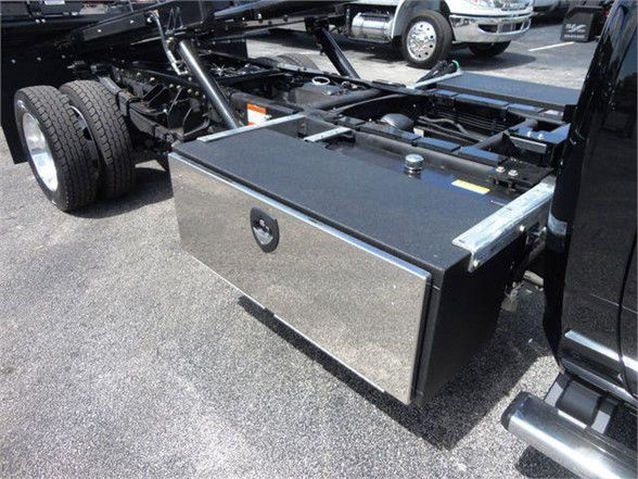 Ram 5500 chassis with a large metallic toolbox mounted on the side rail and fuel/maintenance access compartments visible.