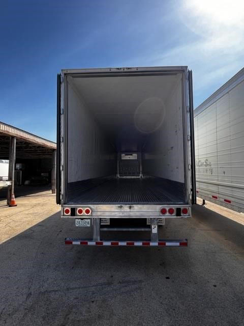 Rear view of an open CIMC Cool Globe refrigerated trailer with empty interior, fifth wheel area visible, and rear bumper lights.