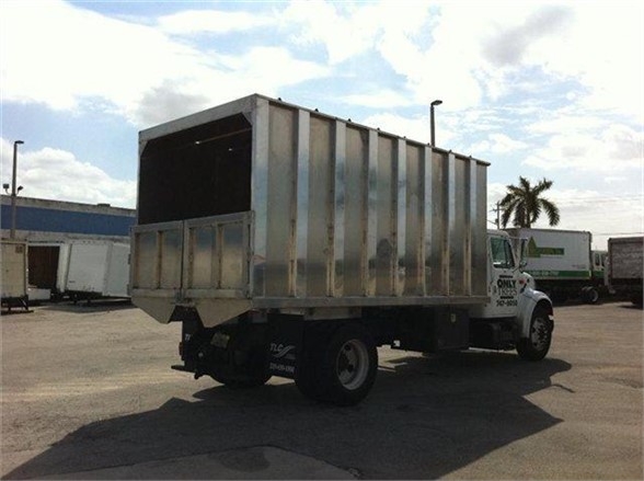 Dump truck with a silver 16 ft dump bed mounted on a white cab chassis, side view showing open-top cargo area and large wheels in a parking lot.