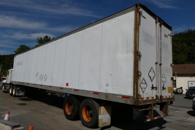 Fruehauf FB9T248 trailer side and rear showing white exterior, dual rear doors, and orange wheels in a yard.