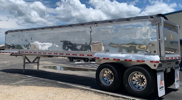 new aluminum end-dump trailer 39 ft, tandem dual axles, reflective strips, polished side panels, rear tailgate with ladder, mud flaps, parked outdoors