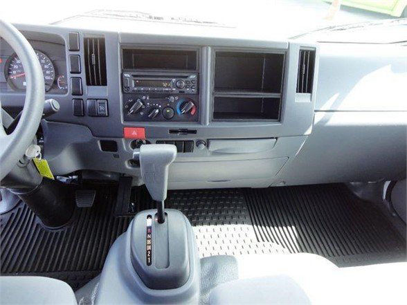 Isuzu NPR HD truck interior showing dashboard with radio, climate controls, gear shifter, and pedals.