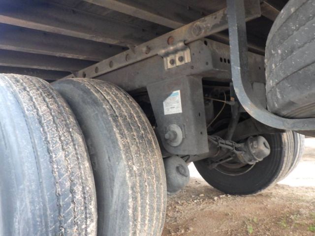 Trailer axle with dual wheels and suspension components visible under a utility trailer.