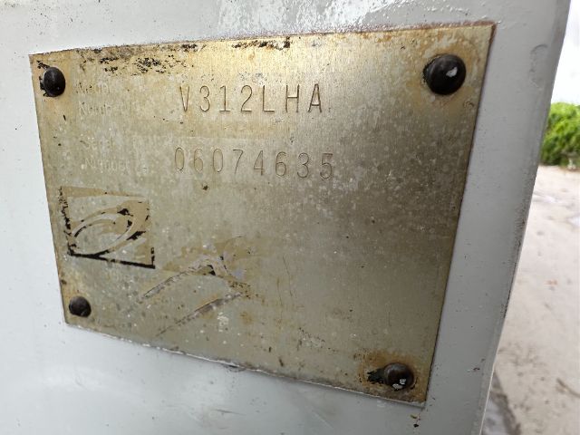 Vehicle plate with stamped code V312LHA and serial 06074635 on a metal plate attached with four screws.
