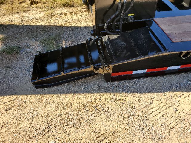 Lowboy trailer part showing a folded ramp with black painted metal and reflective red/white stripes along the edge.
