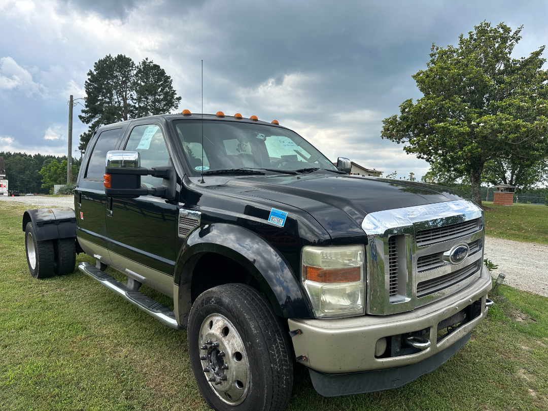  Ford F-450 King Ranch dual rear wheel hauler front three-quarter view showing chrome grille, beige bumper, black body, orange clearance lights, side steps, and large tires.