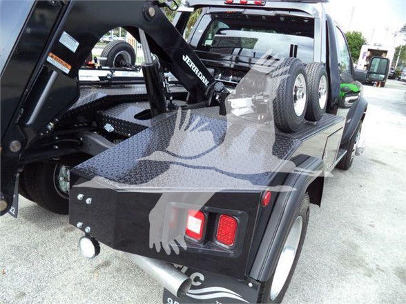 Tow truck bed with a Ram 4500 SLT, heavy-duty towing equipment, spare tires, and rear lights visible on the flatbed.