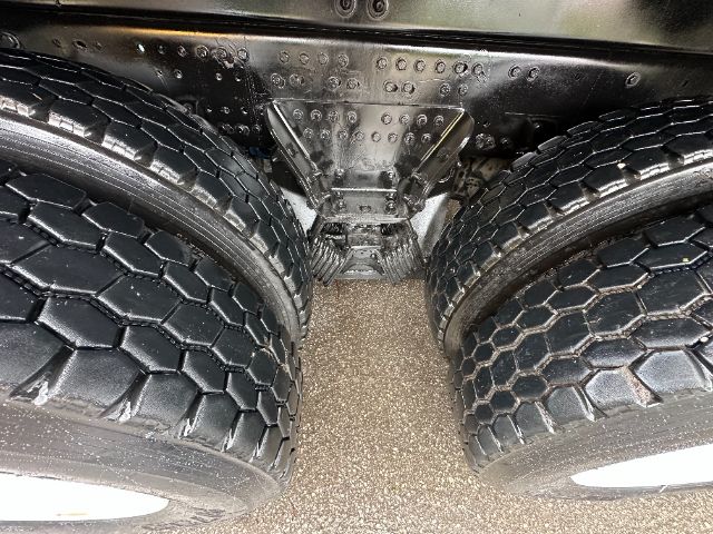 Rear view of a Mack GU713 truck showing dual rear axles with large off-road tires and a central diff/air suspension housing.