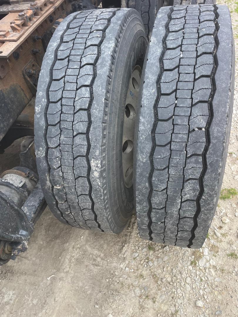 Two heavy-duty truck tires mounted on rear axle, showing tread pattern and wheel rims.